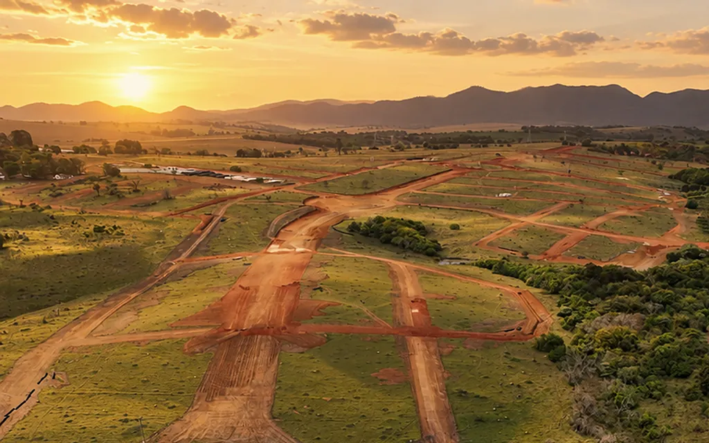 Foto aérea ao pôr do sol do loteamento Imperial da Serra, com as ruas abertas e a serra no horizonte