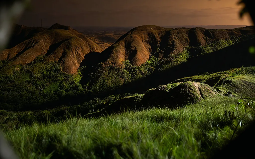Gramado verde com a serra ao fundo no fim de tarde